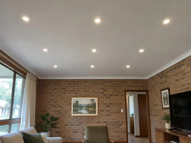 Brick living room with flush ceiling downlights, windows, curtains and a TV in Woodberry
